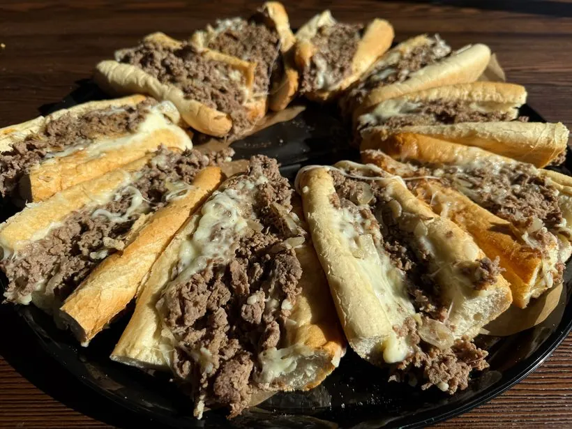 Cheesesteak catering tray — cut cheesesteak sections on a platter, serves 10